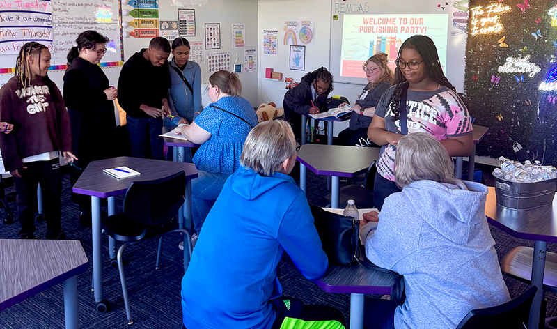 Students sign copies of the books they wrote and published.