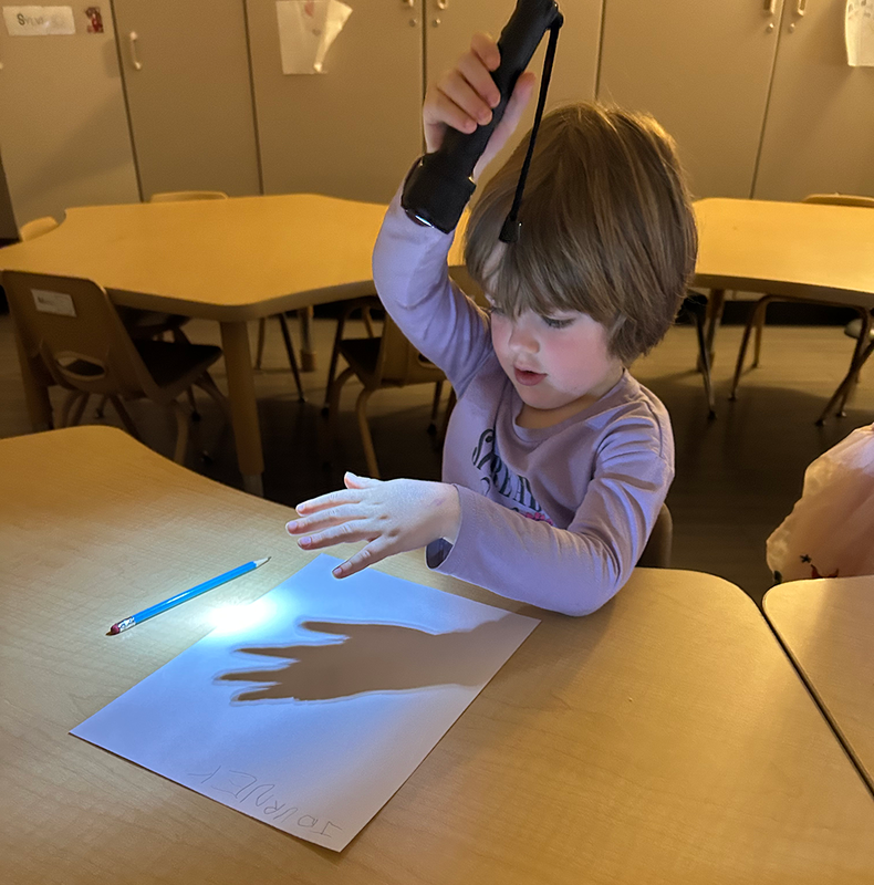 students play with flashlights as they learn about science