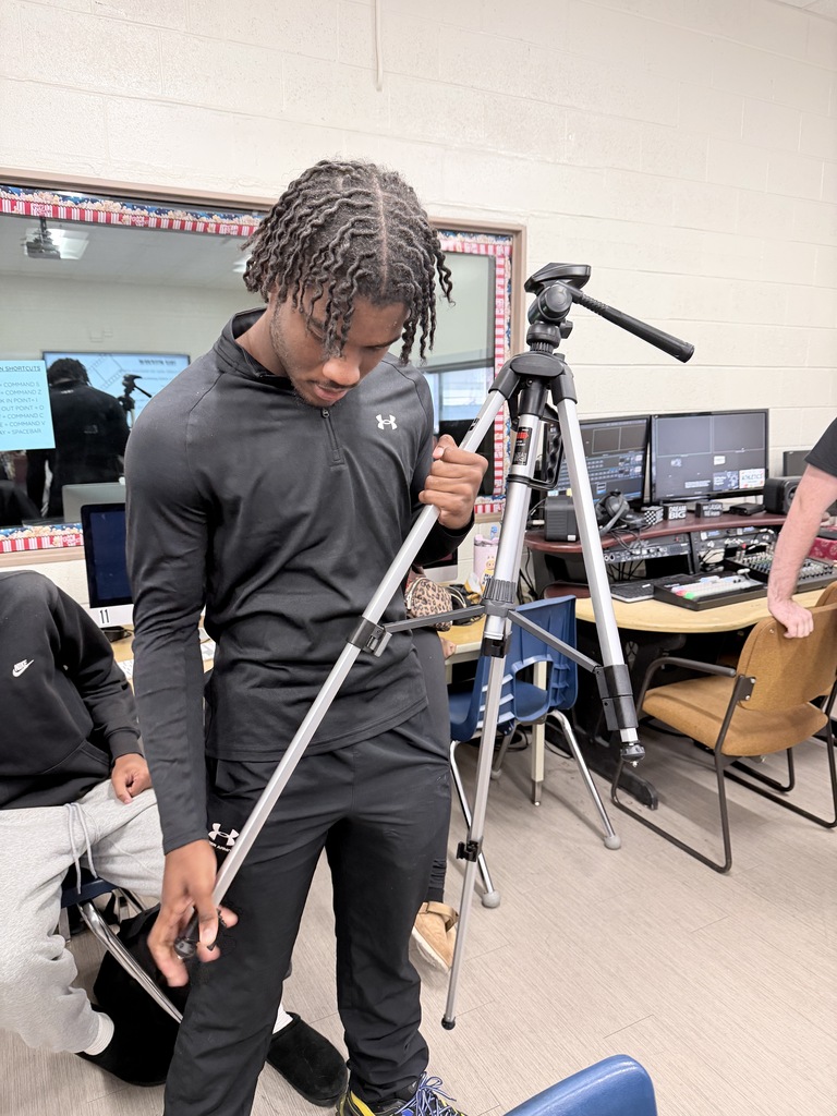 A student practices using a tripod