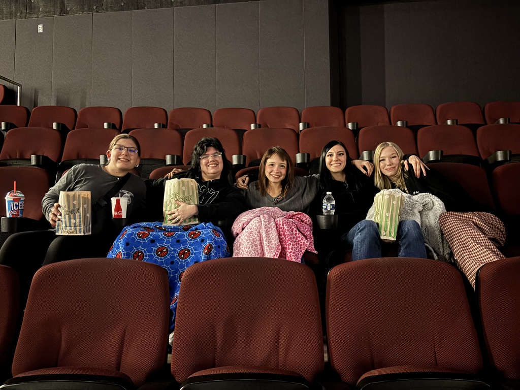 This is a picture of five students smiling in a movie theater… if I had to describe it.