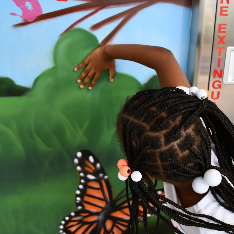 scholars adding handprints to the cube mural