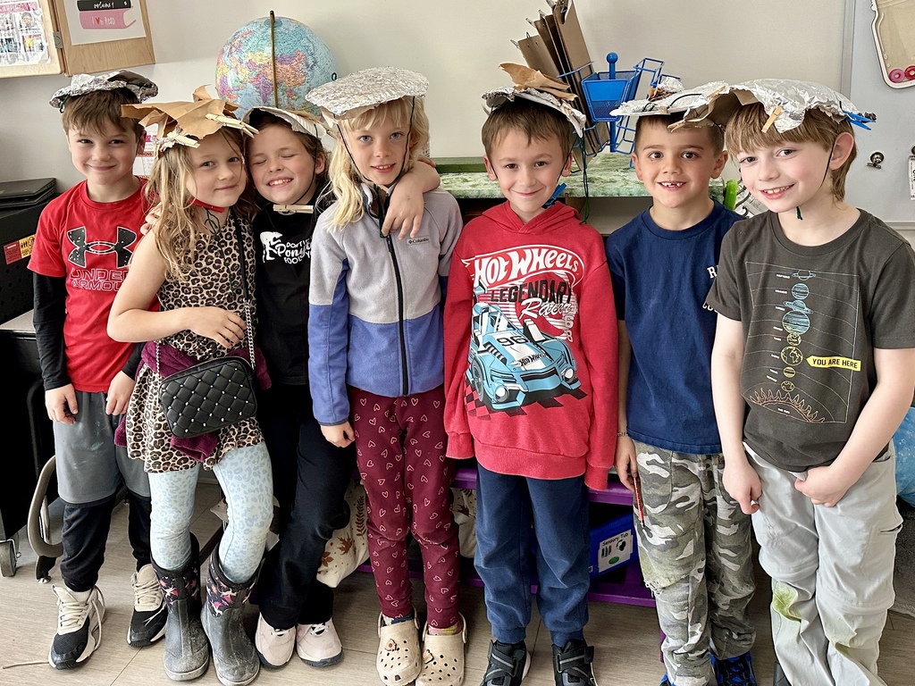 Students wearing sun-resistant hats they created from paper towels, foil, clips, paper plates, and string.