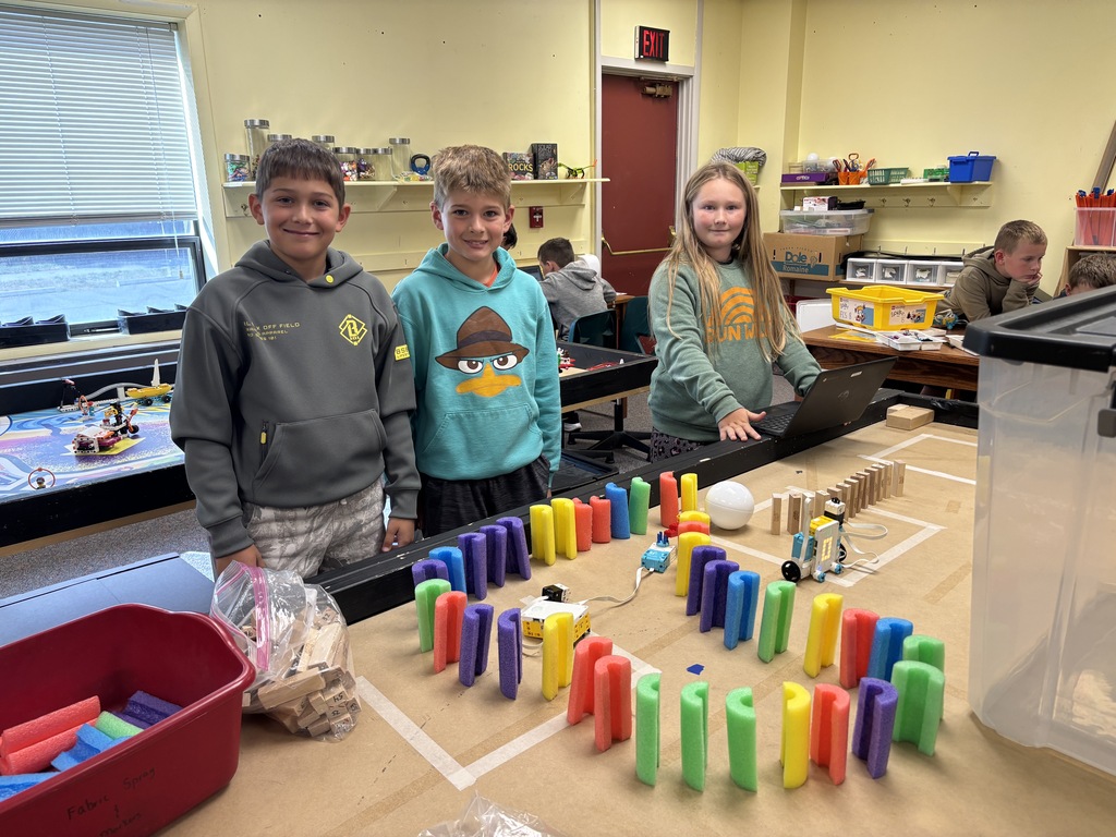 Students around a table with a chain reaction robot set up