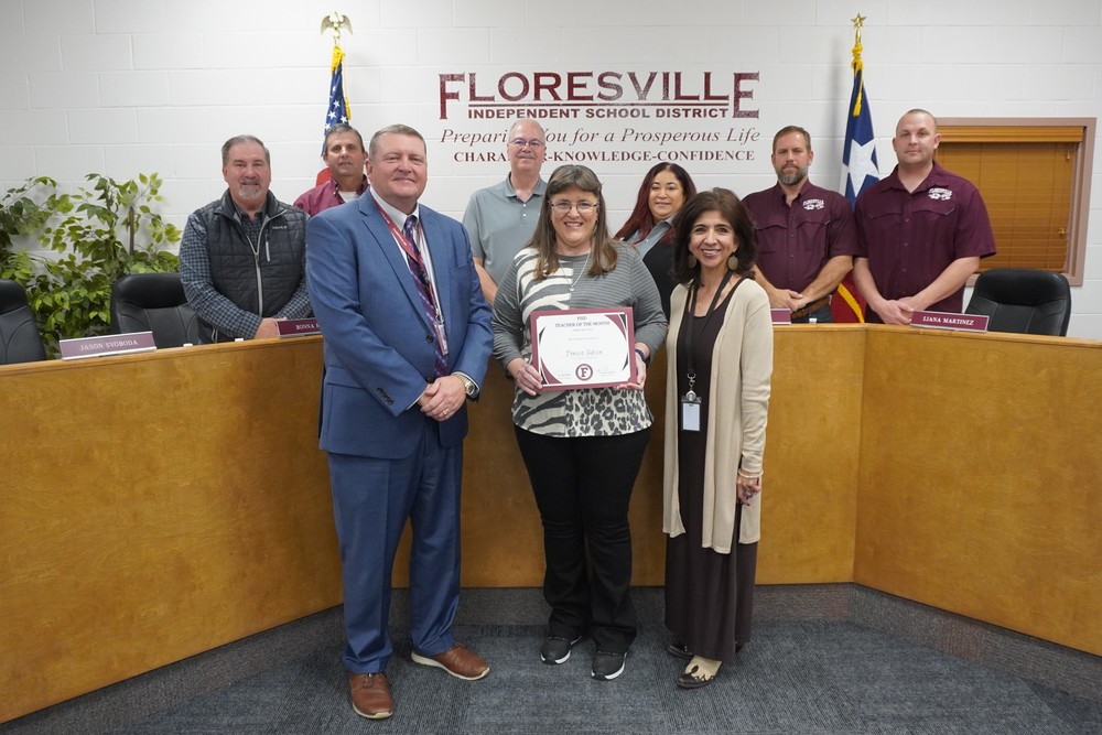 Teacher holding certificate in front of board members
