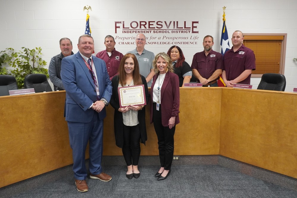 Teacher holding certificate in front of board members