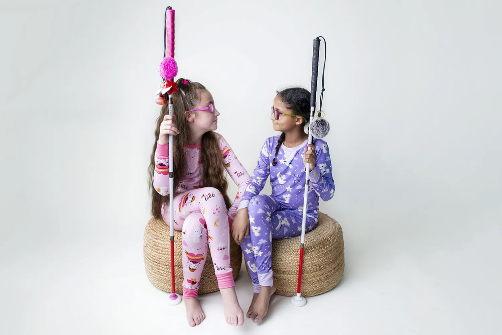 Mackenzie and Penelope wearing Pixies pajamas, sitting  together holding their canes.