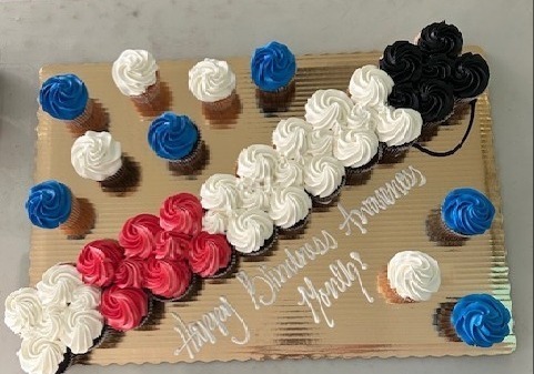 Cupcakes in the shape of a white cane with the words, "Happy Blindness Awareness Month" written in white icing.
