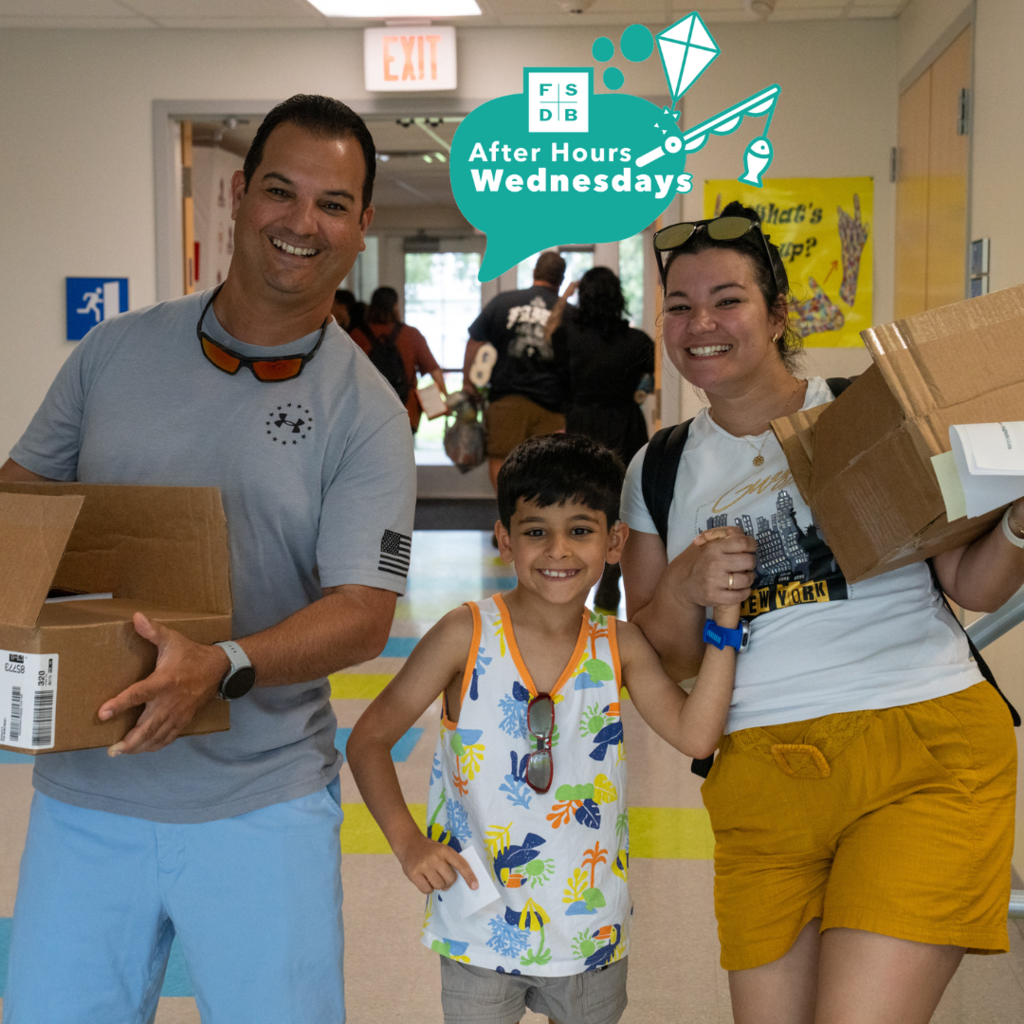 A deaf elementary student is smiling with his parents holding boxes inside the hallway of Gore.