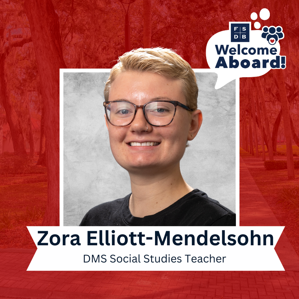 Zora is wearing a solid black shirt smiling for her photo with a silver backdrop and red background. Below the picture says "Zora Elliott-Mendelsohn, DMS Social Studies Teacher"
