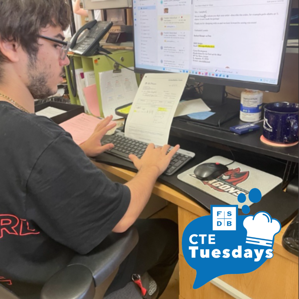 A student is working on a email at the desk in D&B Designs.