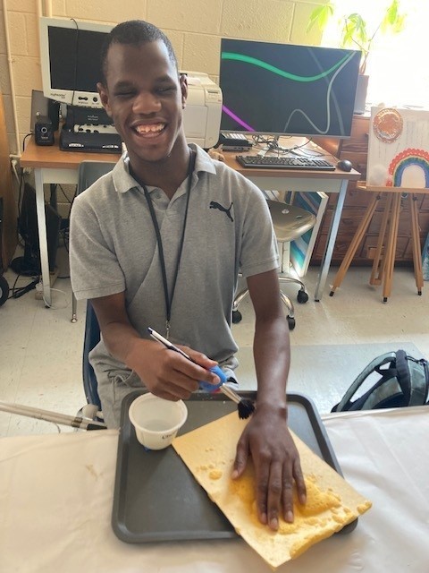 Zachary smiles as he feels a new pattern form on his swell paper after adding water.