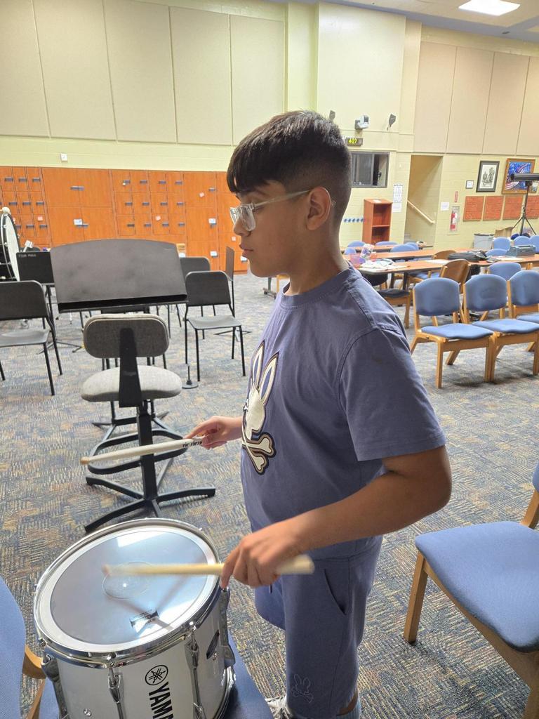 Jayden leads the other students from a snare drum during Drumline practice.