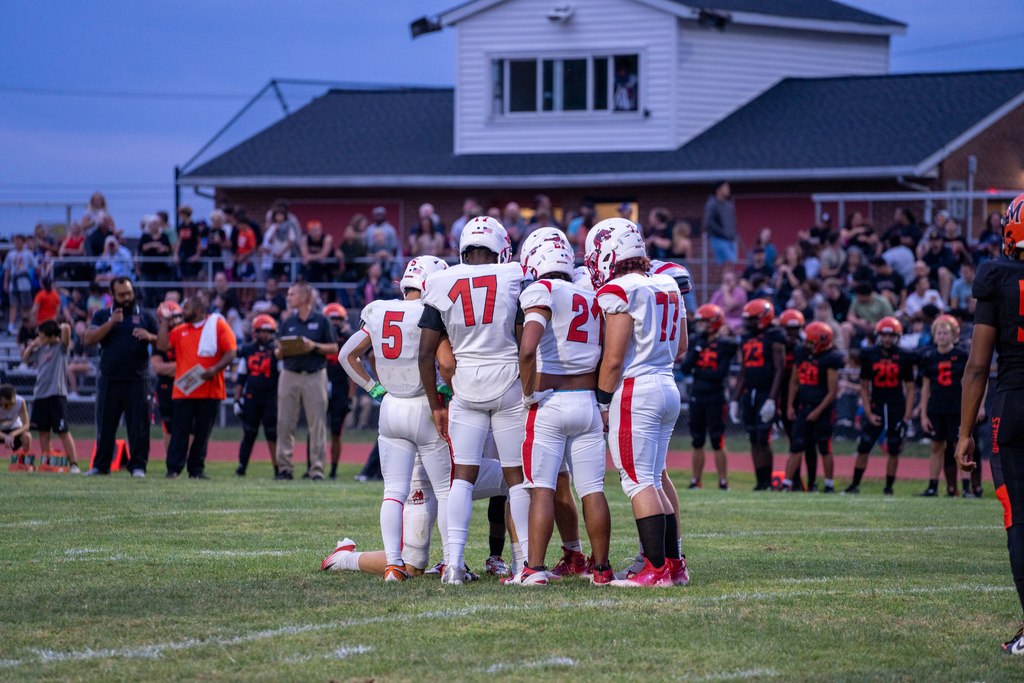 FSDB football players gather around in a hut discussing their next play on the field. 