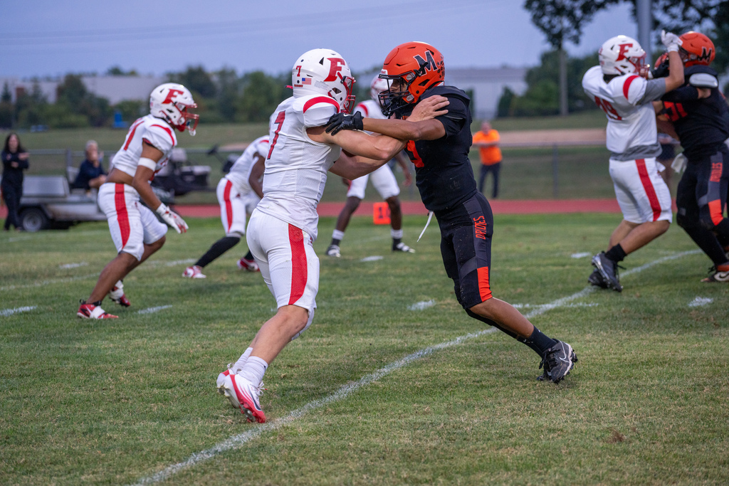 An FSDB football player tackles an MSD football player on the field. 