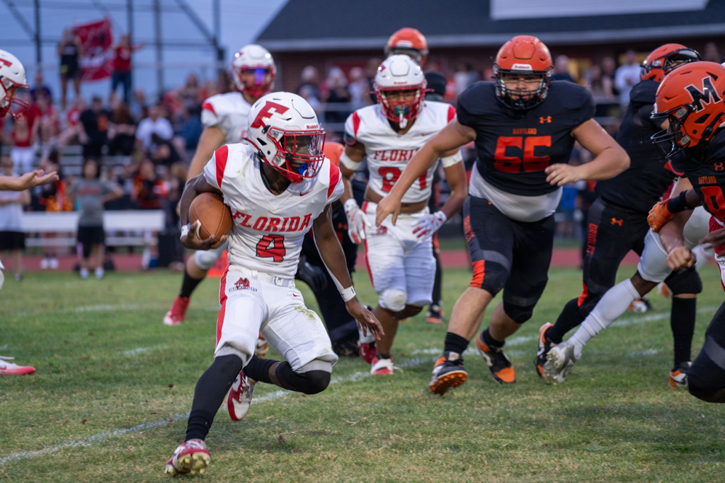 A FSDB football player is running with the ball while MSD players run after him on the field. 
