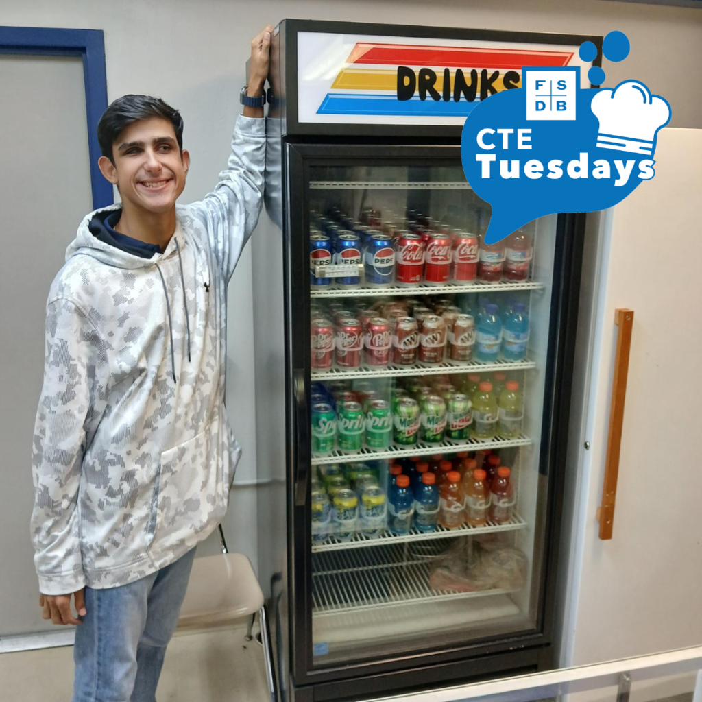 Student worker Damian stands next to the freshly stocked drink cooler in Raymond’s Warehouse. Behind the cooler’s glass door, Damian organized the drinks neatly by type with their logos facing the customer. Retail business principles such as inventory presentation and rotation are part of what students learn in the After School Work Program.
