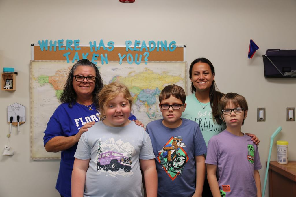 Two staff members smile with three elementary students as they are all dressed in colors relating to the elements. 