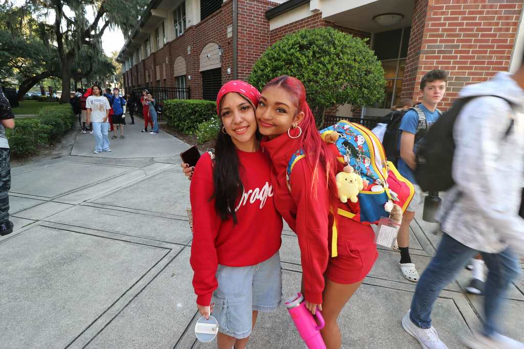 Two deaf students are dressed in all red resembling "fire" smiling for a photo outside of Pope. 