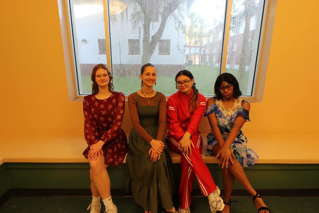 Four deaf high school students are dressed in the colors of the elements posing on a bench inside Pope. 