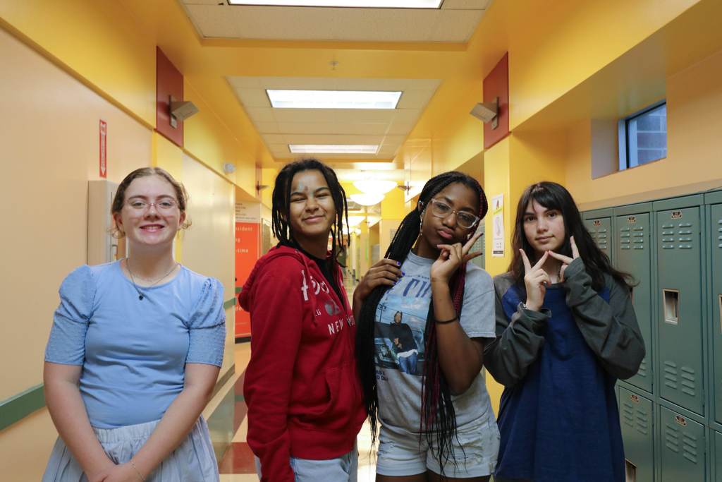 Group of four students smiling and posing with peace signs in the hallway of Pope. 