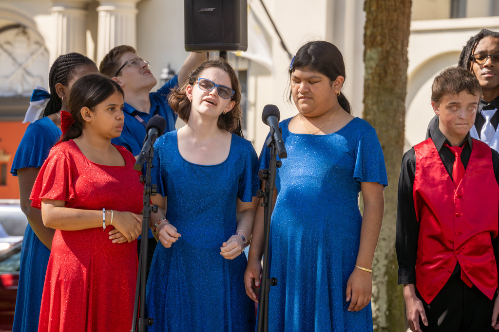A close-up photo of three girl singers wearing blue and red dresses in the plaza outside downtown St. Augustine.