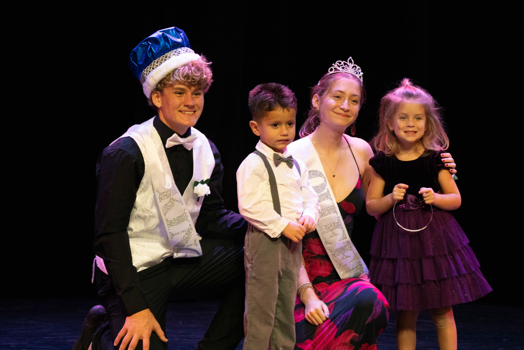 The senior King and Queen are smiling with two ELC students on stage in Kirk.