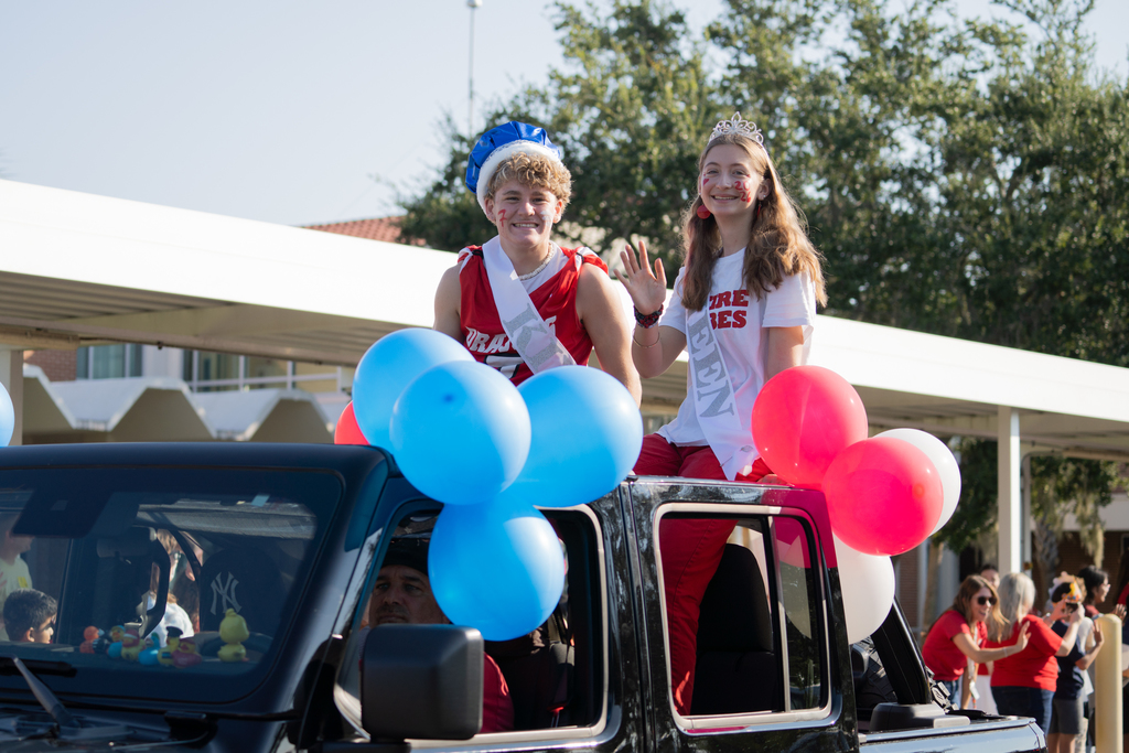 Homecoming Court King and Queen sit in the back of the Jeep Wrangler waving for the camera. 