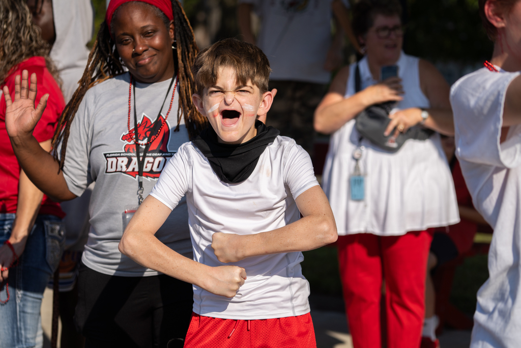 A student getting excited outside as the parade walks by him. 
