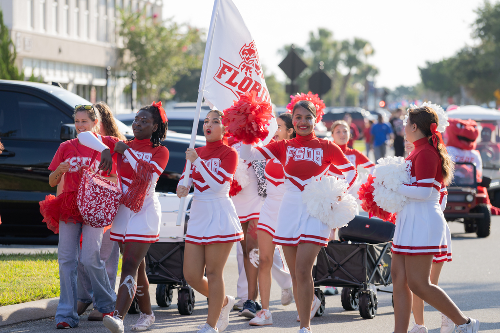 FSDB Cheerleaders hold a Dragons flag and waving with their red and white pom poms outside during the parade. 