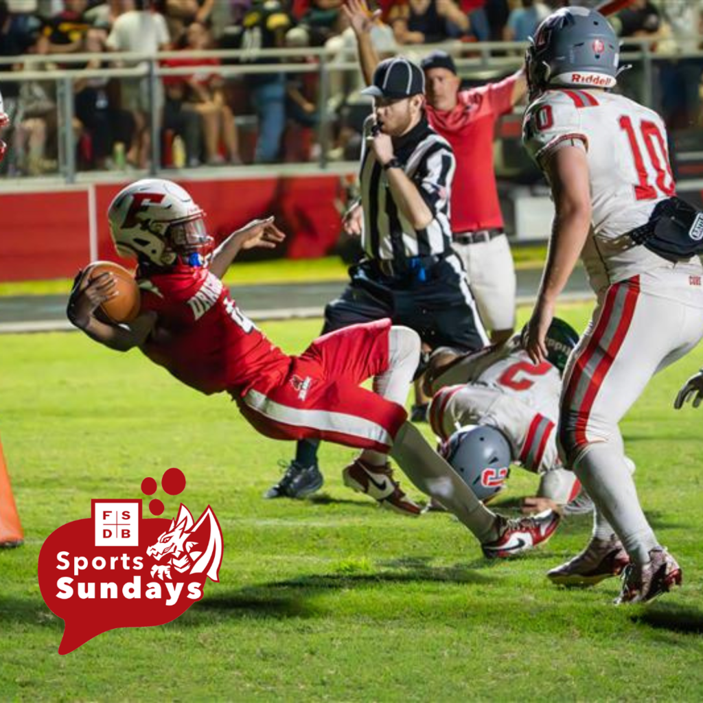 A FSDB football player is scoring a touch down while the other team tries to tackle him on the Usina Football field.