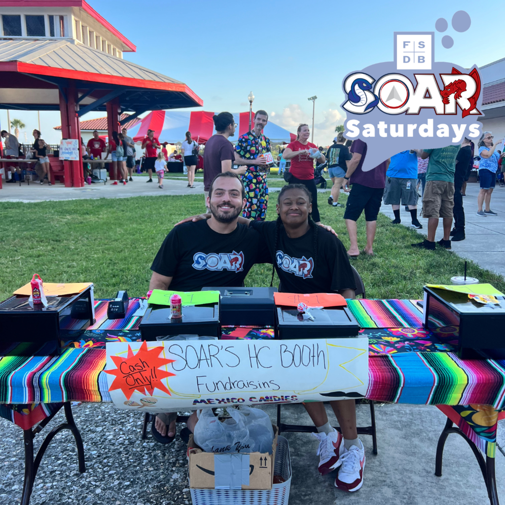 SOAR student smiling with a SOAR teacher at their booth selling Mexico candy outside Usina Field during the Homecoming football game. 