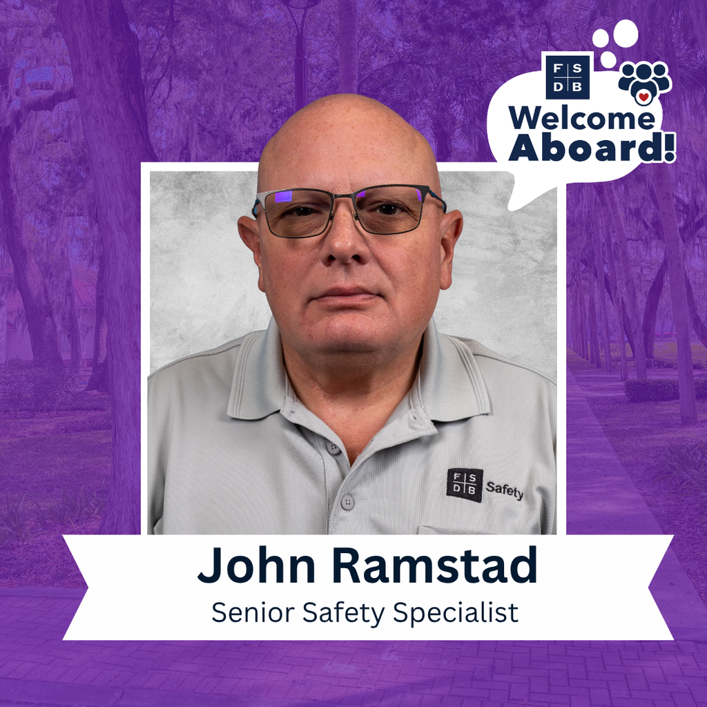 John is wearing a light gray color shirt with "FSDB Safety" on the right of his shirt smiling for his photo with a silver backdrop and purple background. Below the photo is a white textbox that says "John Ramstad, Senior Safety Specialist" 