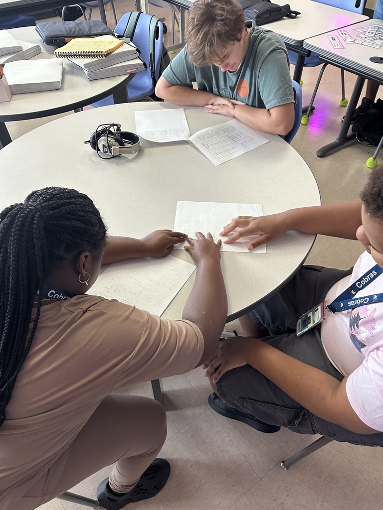 Sophia, Takiah, and Lucas  sit together around a round table, studying their braille and large print notes.