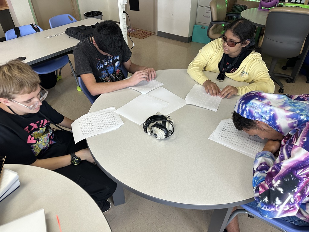 Nicholas M, Facundo, Danna, and Ryan sit together around a round table, studying their braille and large print notes.