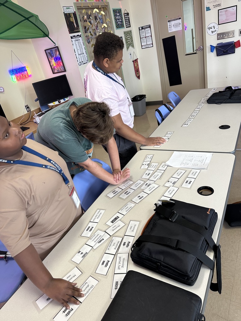 Takiah, Sophia, and Lucas work together reading and moving the paper dominoes (with large print and braille).