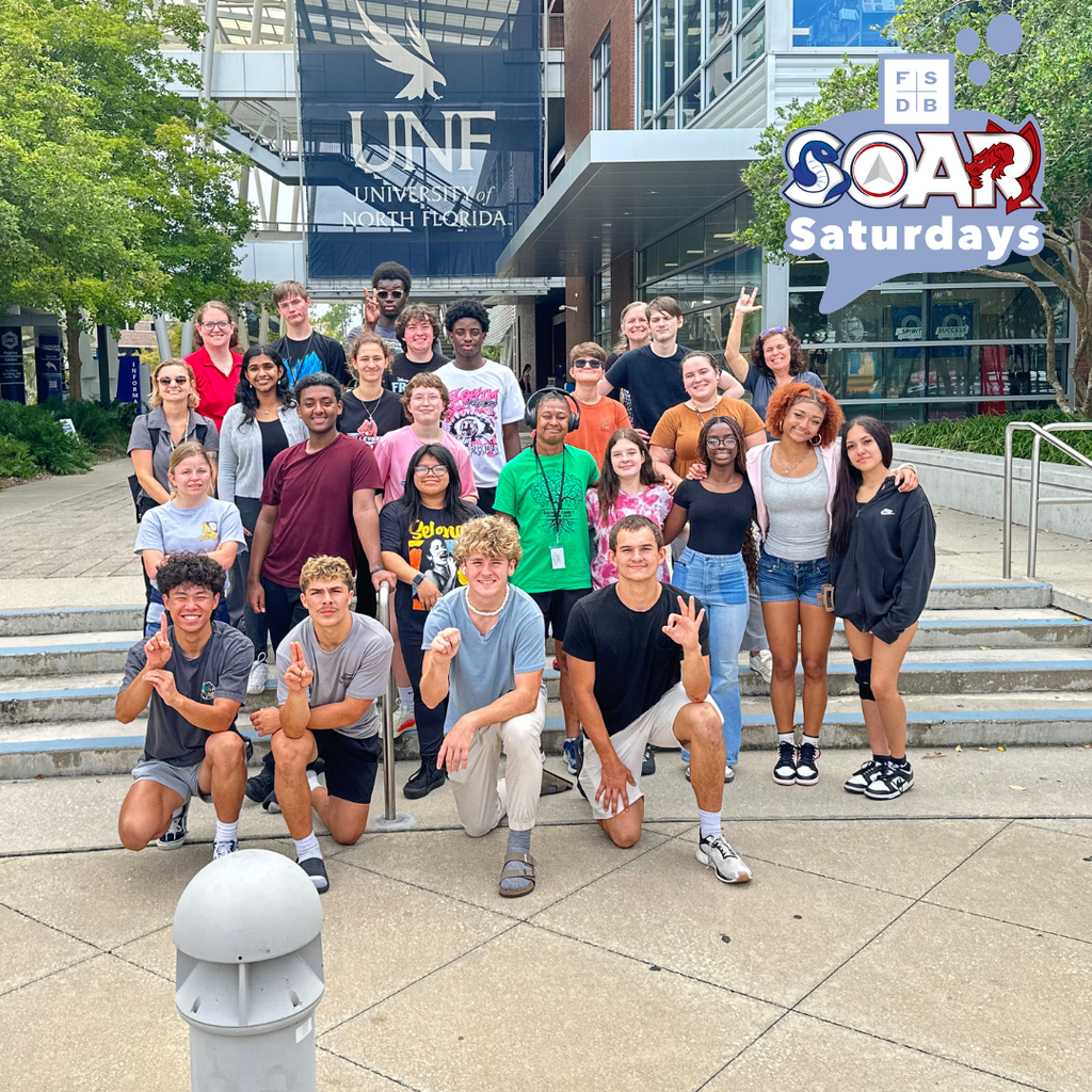 Group of deaf high school and SOAR students smiling for a photo in front of the UNF sign.