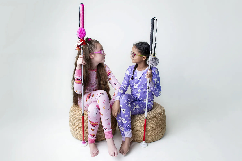 Mackenzie and Penelope wearing Pixies pajamas, sitting  together holding their canes. Photo credit: Renelita Montesano.