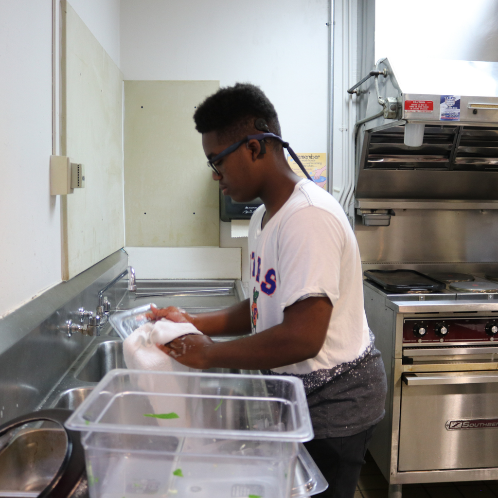 A student washing dishes inside the kitchen. 