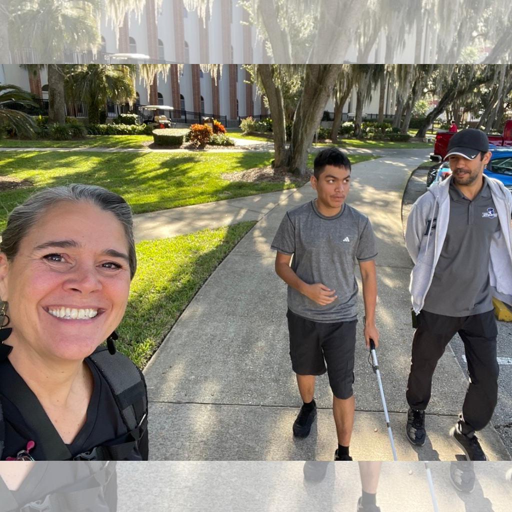 Tracie takes a selfie with a student and O&M staff working on skills outside on campus. 