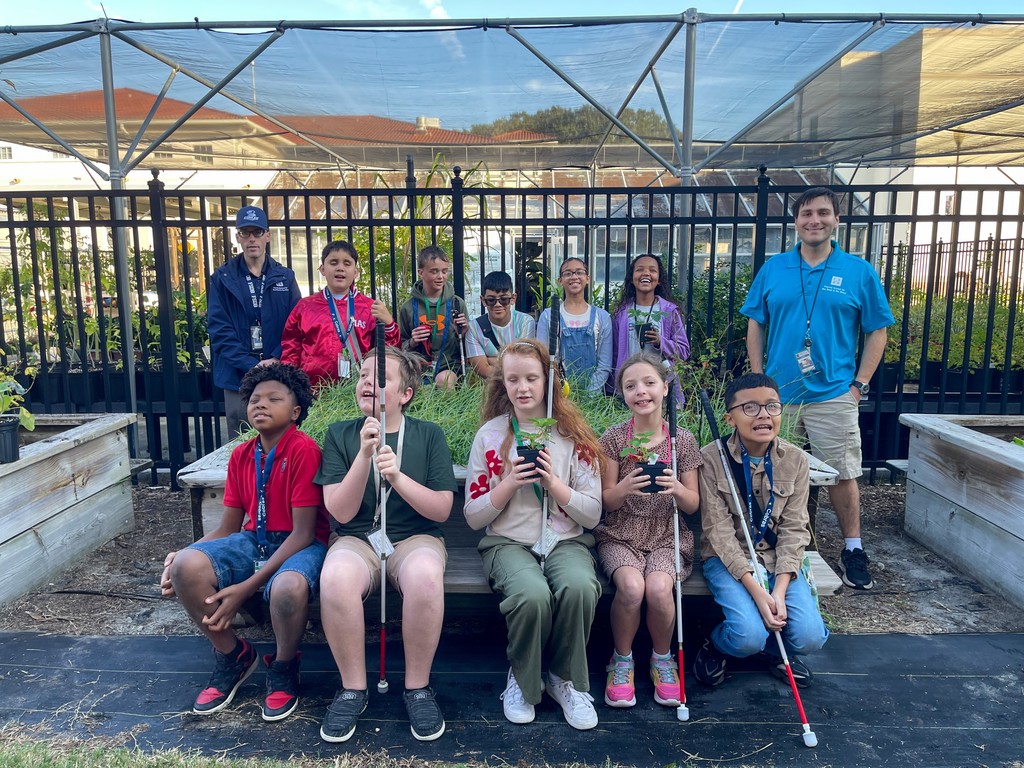 Mr. Ferguson and his class pose with Mr. Podlisney at the Garden Center around some plants.