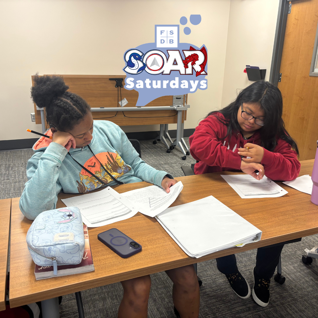 Two SOAR students working together giving peer feedback inside the classroom.