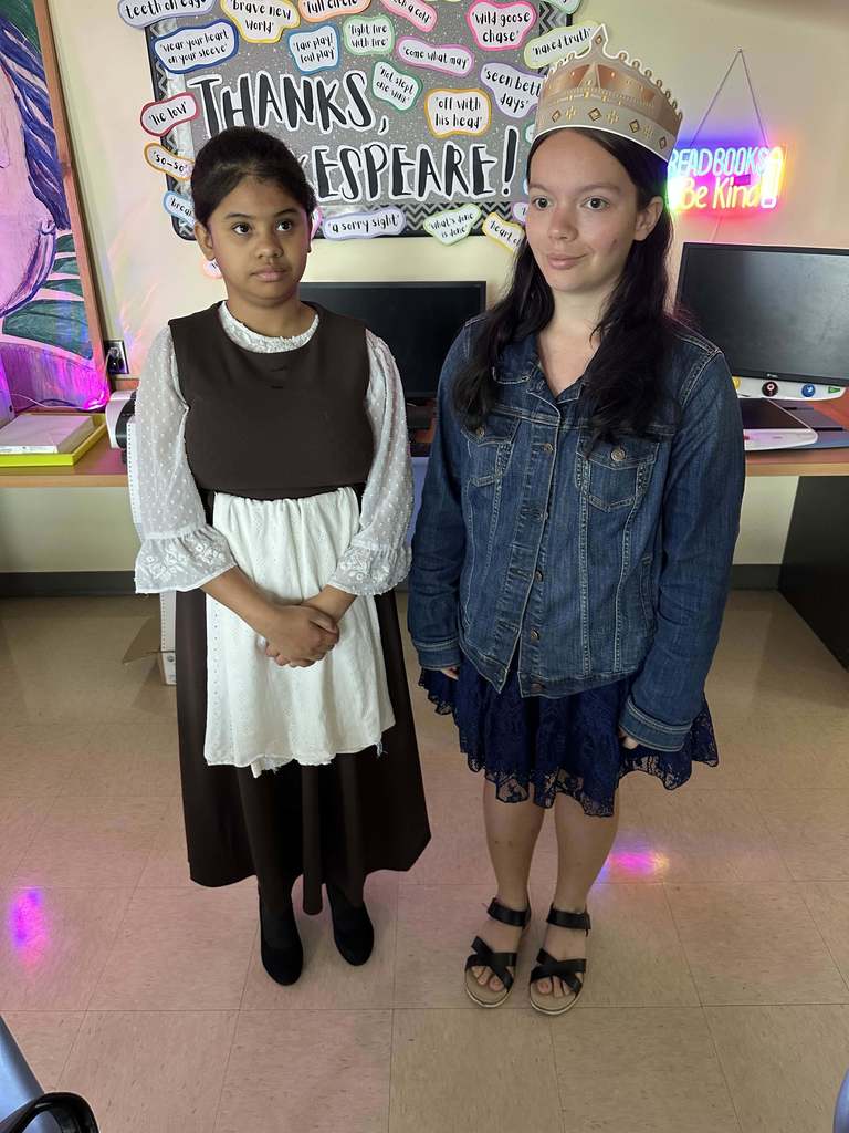 Two students are dressed like medieval times smiling for a photo inside the classroom. 