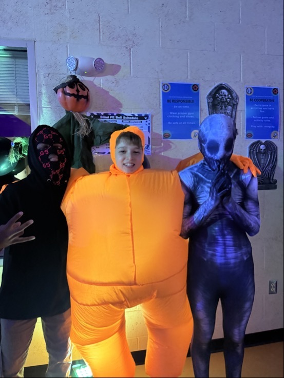 Three students are dressed up for halloween pose for a photo together inside the dorm. 