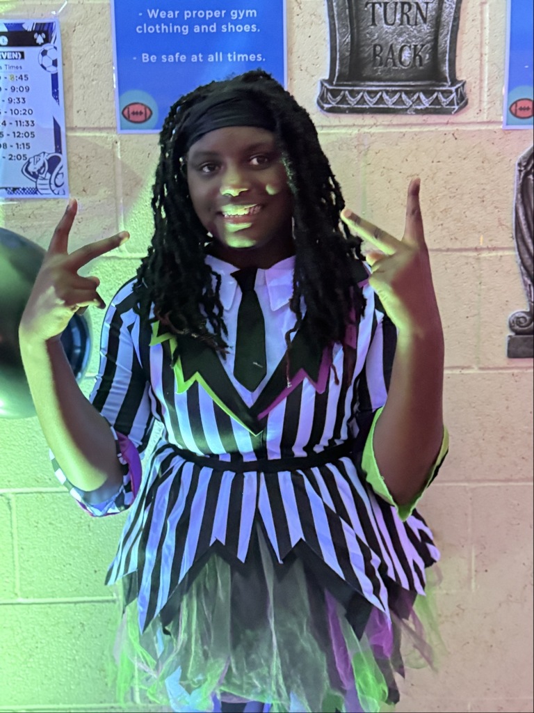 A student dressed like Beetlejuice hold peace signs as she poses for a photo inside the dorm. 