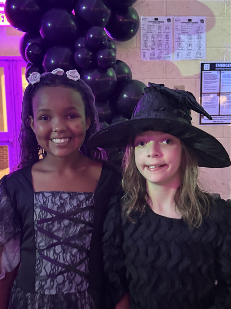 Two students dressed up for Halloween smile together for a photo inside the dorm. 