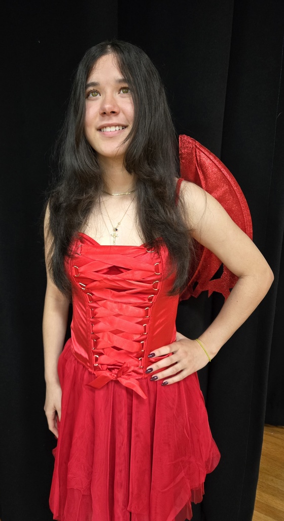 A student is dressed like the devil in a red dress as she smiles for her photo. 