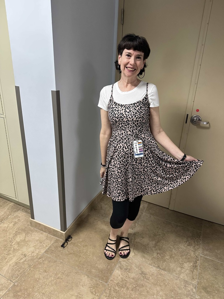 A staff member dressed in cheetah print pose for her photo outside in the hallway. 