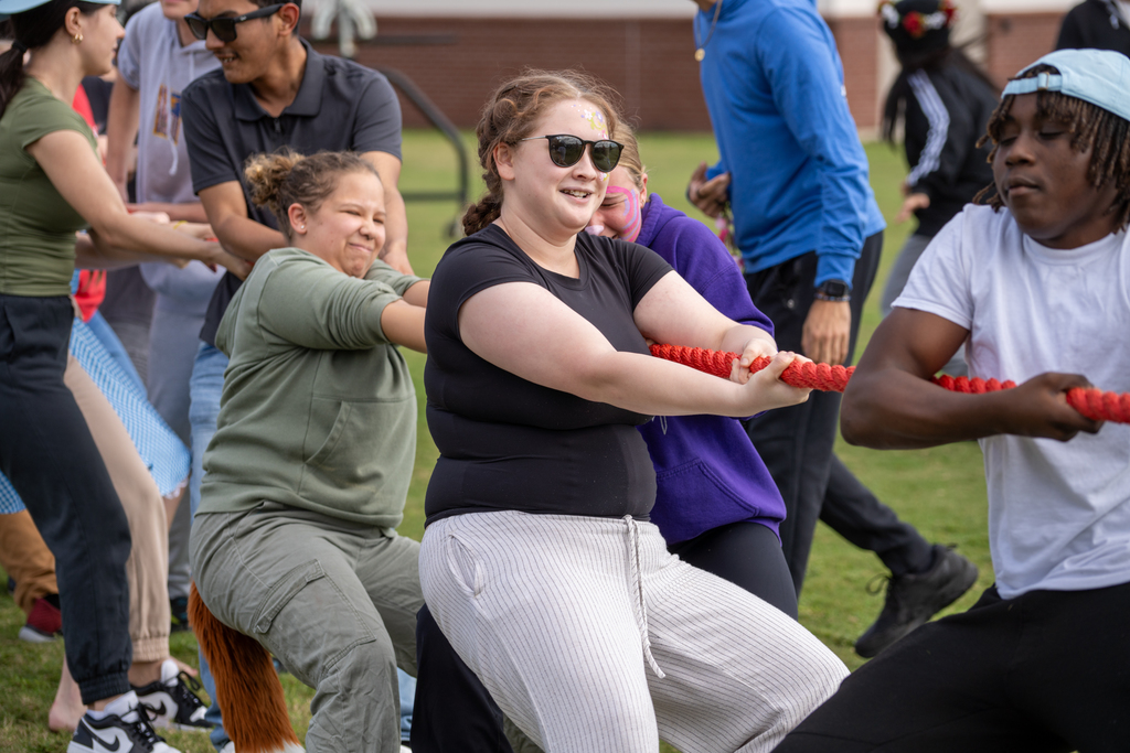 A student is pulling on the rope playing tug of war, for her team. 