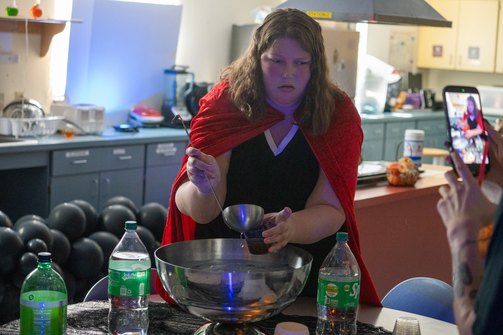 A student is pouring a drink for a staff member inside the cooking classroom. 