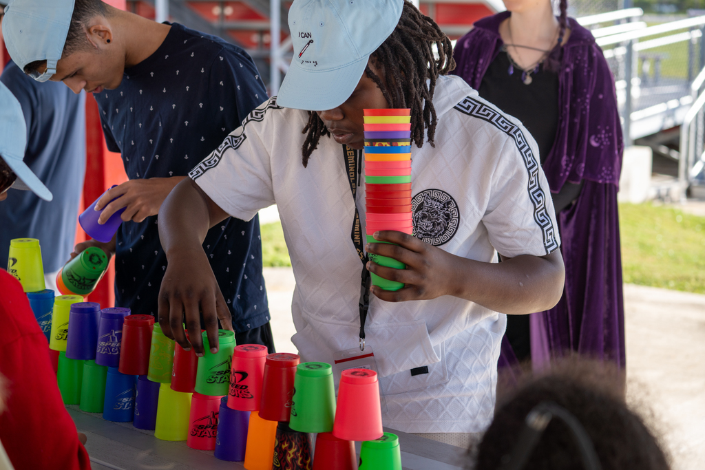 A student is holding cups and trying to make the tallest tower possible. 
